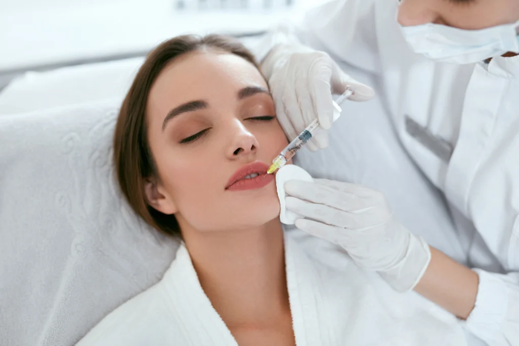 A woman receiving a lip filler injection during a Juvederm lip enhancement procedure.