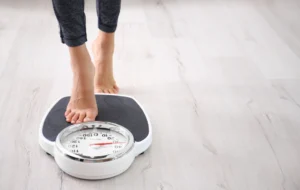 Person stepping onto a scale to check weight progress with Tirzepatide.