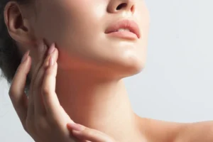 Close-up of a person's jawline and neck with a hand gently touching the side of the face.
